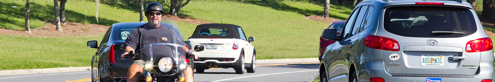 photo of cars and motorcycle going around a curve